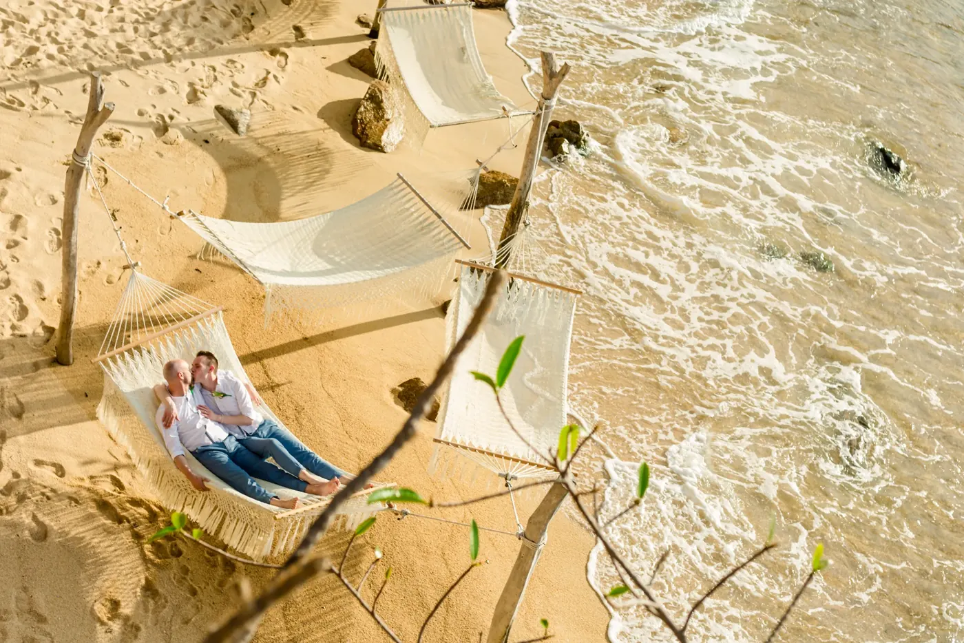 A couple resting in a beach hammock, seen from above